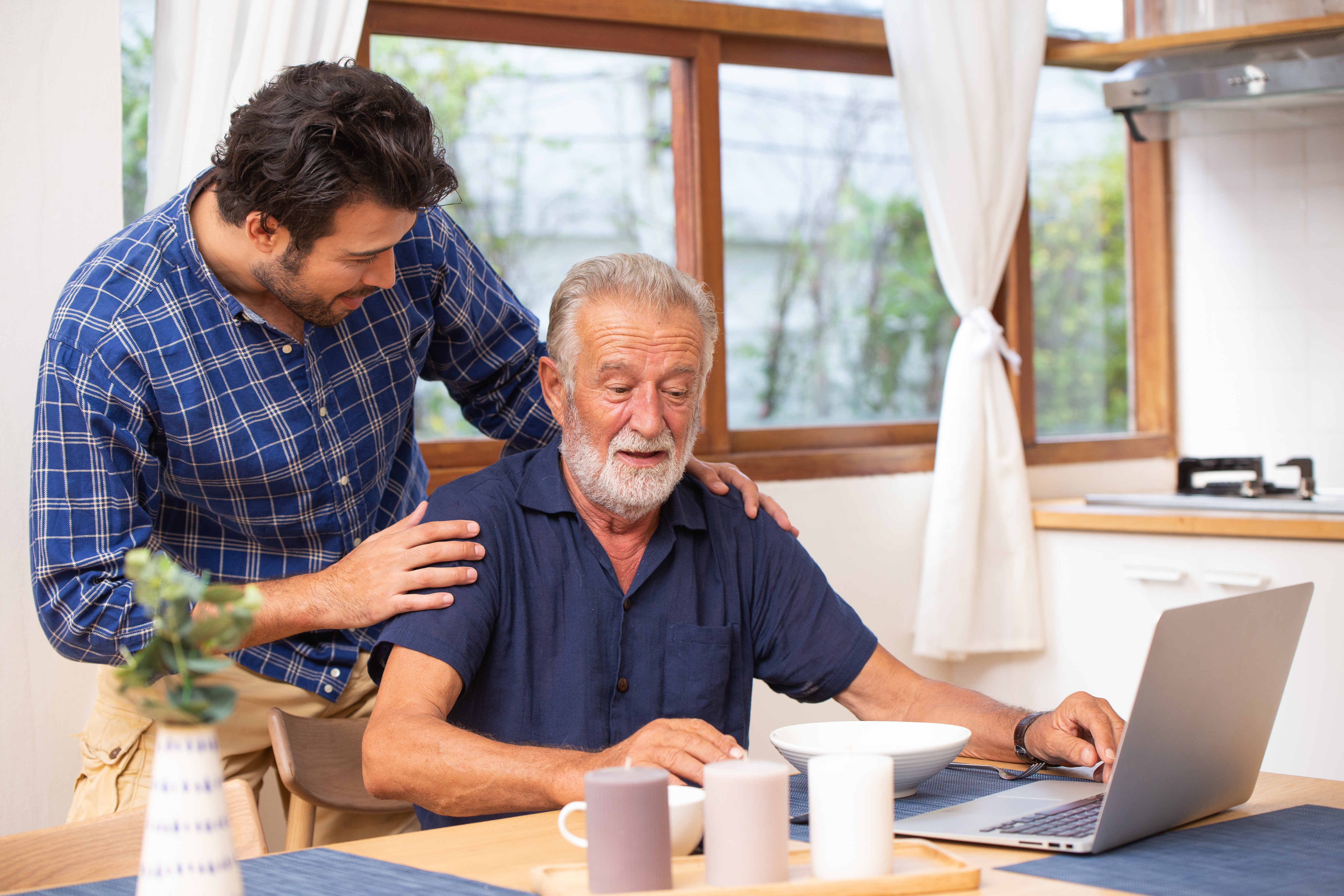 Elder care in home, good mentor healthy smart old man using laptop computer stay at young man.